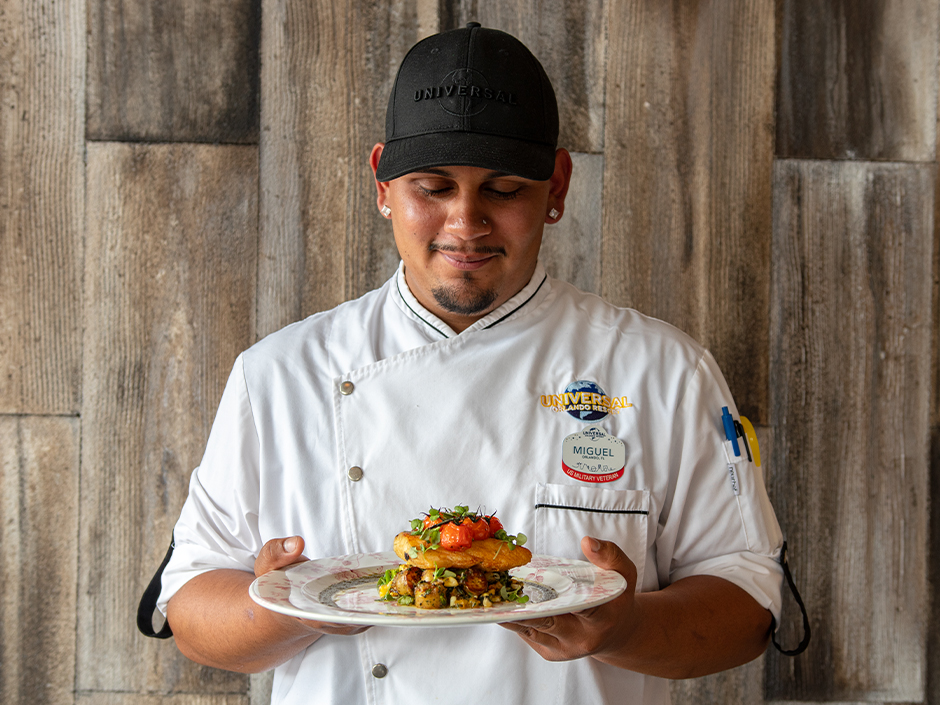 Chef Miguel Ortiz smiling while holding his new dish the Halibut, available at VIVO Italian Kitchen at Universal CityWalk.