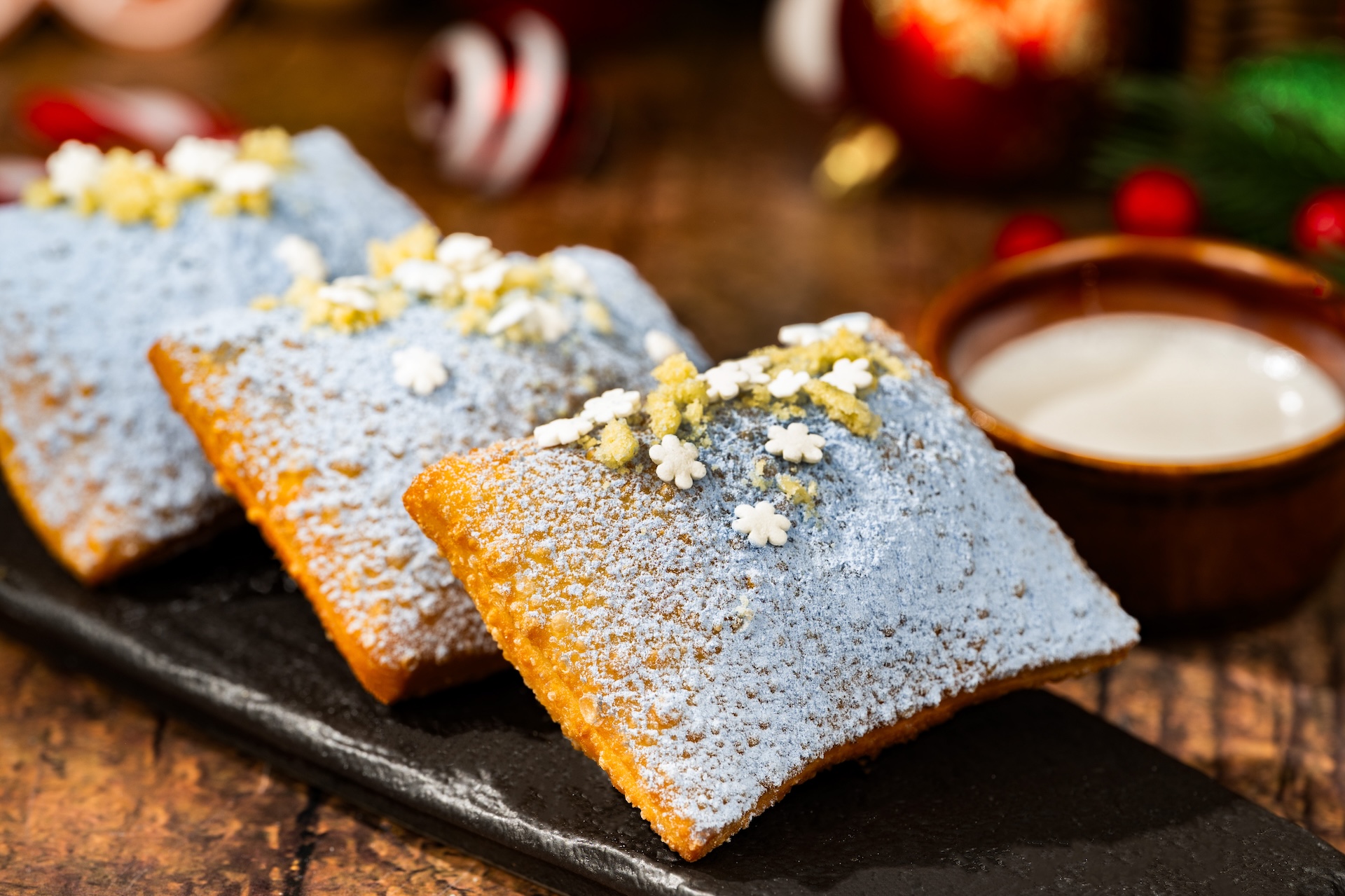 Festive Beignets: Light and fluffy beignets dusted with blue sugar cookie dust and served with cookie butter icing