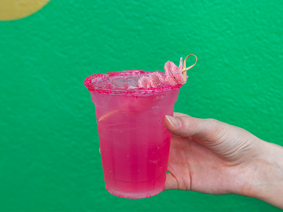 A hand holding a cup of the Popular Potion in front of a green wall at Universal Studios Florida for