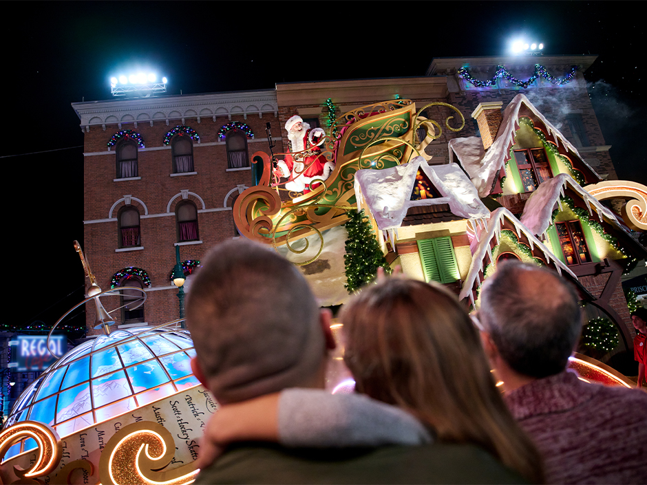 Santa waves at guests from a Macy's Universal Holiday Parade float