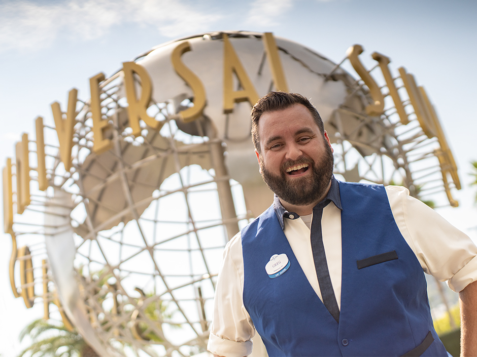 Universal Studios Hollywood VIP tour guide smiles in front of Universal Studios Hollywood globe.