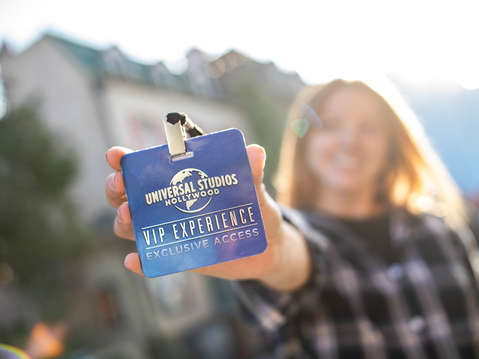 Woman holding blue VIP Experience pass to camera.
