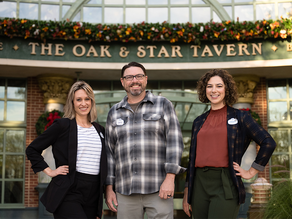 From left to right, Stephanie Trilli, Curtis Hopkins, Lindsey Ellis, standing in front of a holiday-decorated Oak & Star Tavern