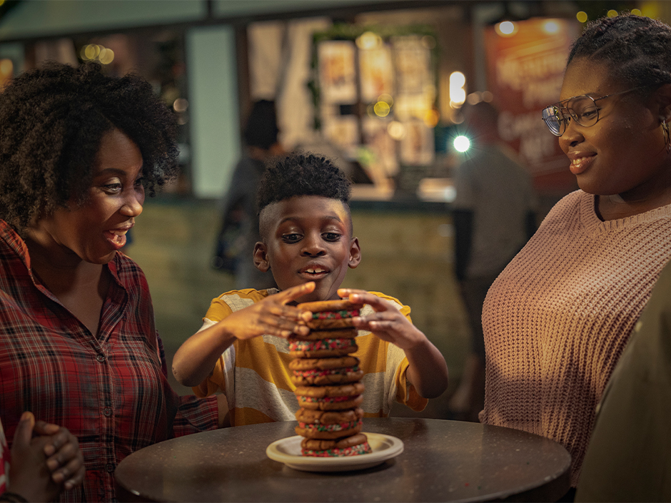 A child sits between his parents and enjoys a holiday treat