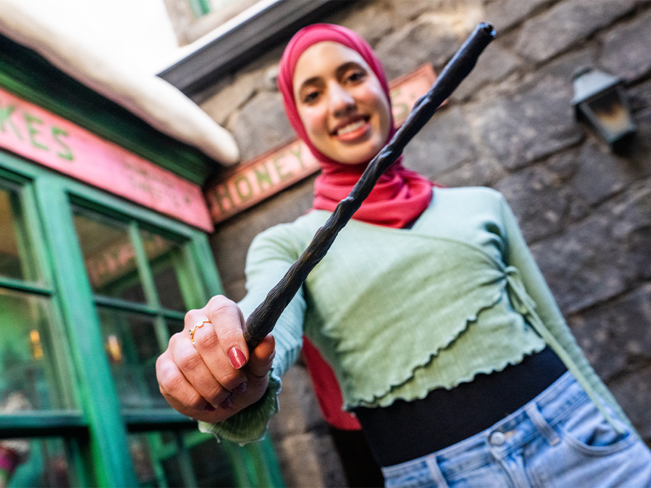 A woman holds an interactive wand in the Wizarding World of Harry Potter.